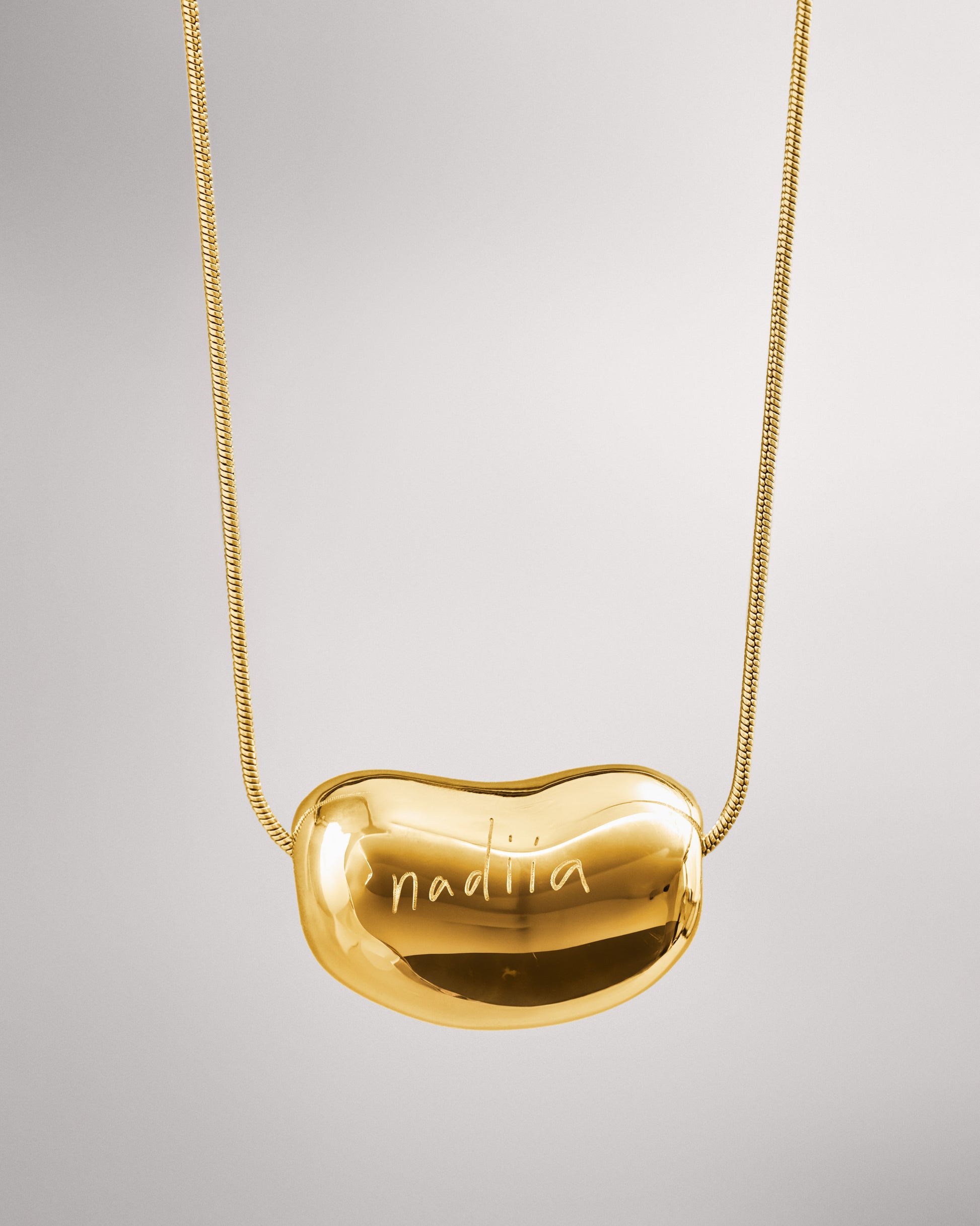 Купіть виріб ручної роботи Golden "Bean" Pendant від Nadiia World. Ідеальний вибір для додавання вишуканості та шарму до вашого житлового простору або колекції особистих аксесуарів.