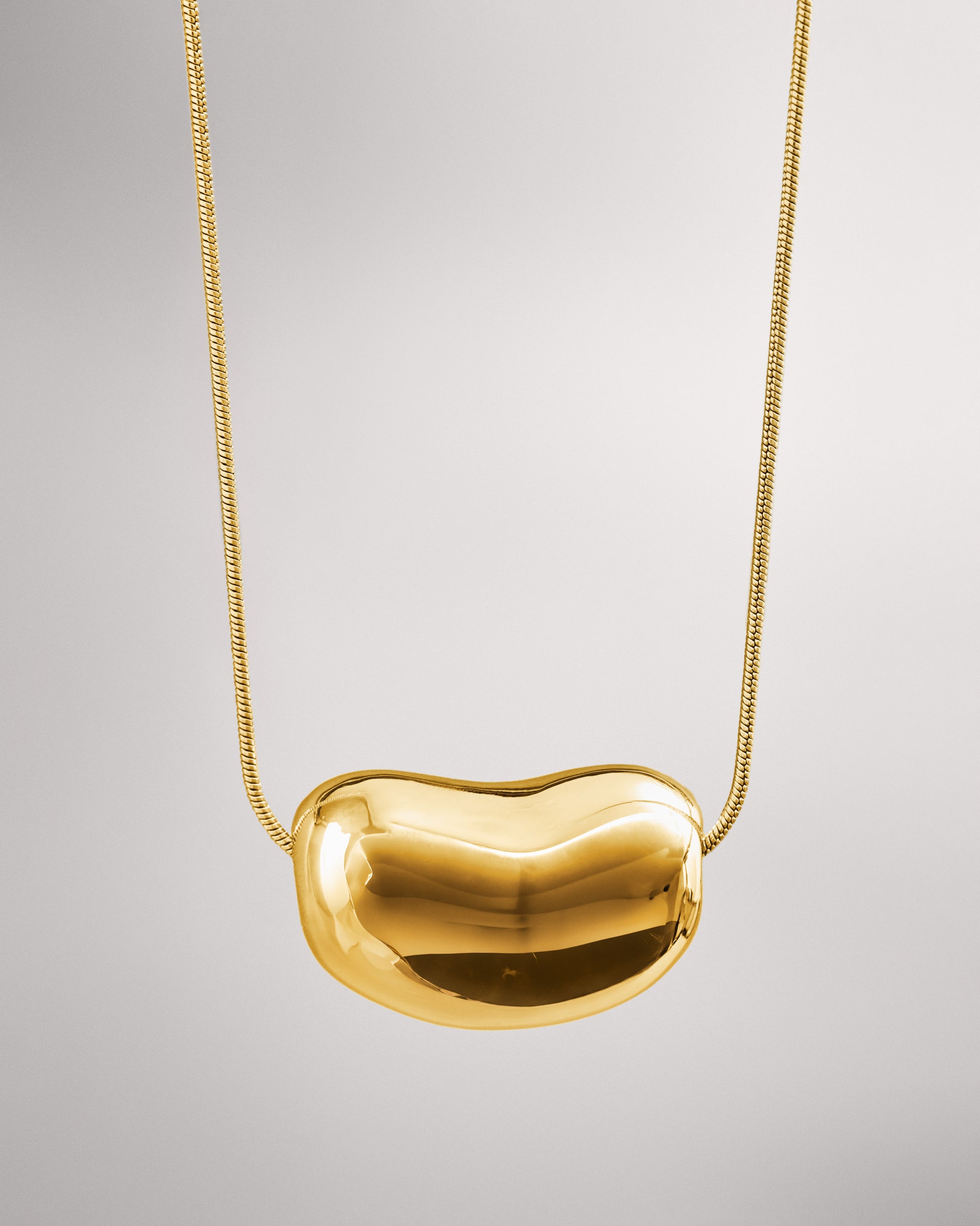 Купіть виріб ручної роботи Golden "Bean" Pendant від Nadiia World. Ідеальний вибір для додавання вишуканості та шарму до вашого житлового простору або колекції особистих аксесуарів.